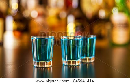 Popular Blue Drink Shot Kamikaze On The Background Of The Bar With Bottles, A Refreshing Drink