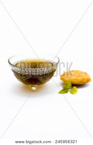 Jaggery Or Gud With Its Syrup In A Transparent Bowl Isolated On White.