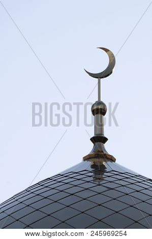 The Top Of The Mosque Minaret. The Symbol Of Islam Is A Golden Crescent Moon On A Blue Evening Or Mo