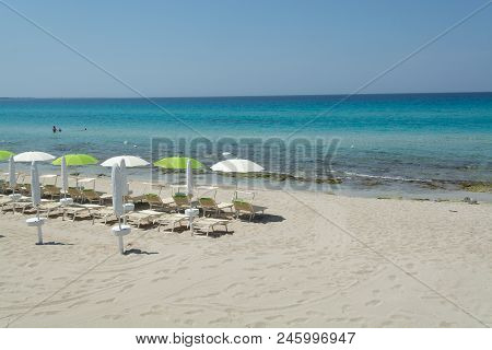 Beach Equipment, Chairs And Sun Umbrella On White Sandy Beach With Light Blue Sea Water, Beach Vacat