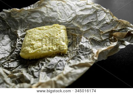 Soft Yellow Butter On The Wrapper And A Black Table. Crumpled Kraft Paper, Wrapping Paper, Greasy Oi