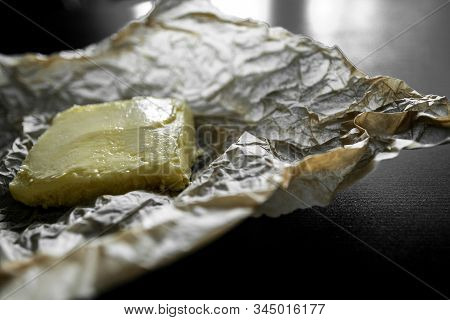 Soft Yellow Butter On The Wrapper And A Black Table. Crumpled Kraft Paper, Wrapping Paper, Greasy Oi