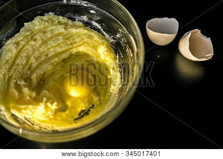 Homemade Cakes, Pastry And Pie Dough Made From Sugar, Butter And Raw Egg. Eggshell On A Black Backgr