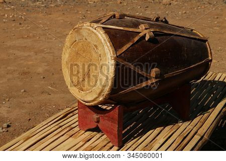 Close Up View Dholak, A Traditional Musical Instrument On A Bamboo Bench And Wooden Placemat