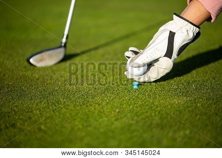 Professional Golf Player Setting Up The Golf Ball On A Stand On Grass During Golf Match