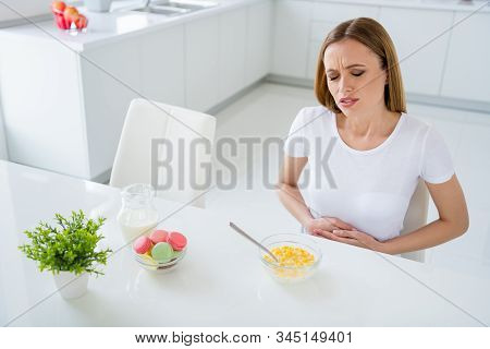 женщина держится за живот, ей плохо, рядом стоит тарелка с едой