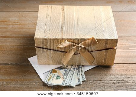 Gift Box And Dollar Bills On Wooden Table