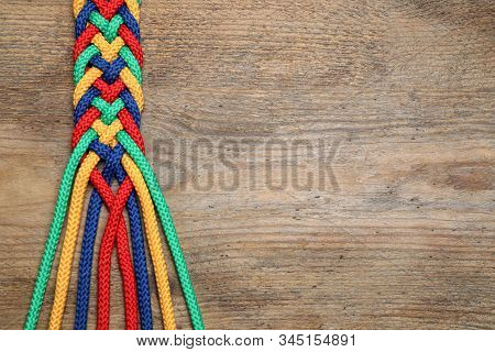 Top View Of Braided Colorful Ropes On Wooden Background, Space For Text. Unity Concept