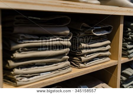 Pile Of Beige Jeans On A Shop Window In The Store. Folded Jeans Are On The Shelf. A Stack Of Classic