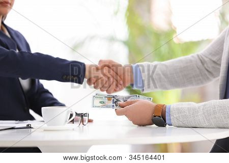Man Shaking Hands With Woman And Offering Bribe At Table In Office