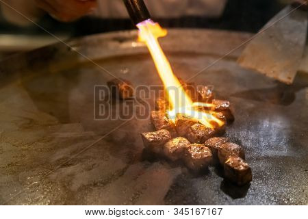 Cooking of beef teppanyaki recipe japanese grilled beef on cooking pan with scraper and gas burner flame