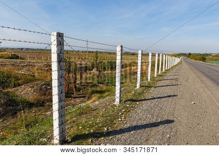Barbed Wire Fence Along The Road, State Border Between Kyrgyzstan And Uzbekistan