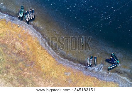 Top View Of Groups Of Fishing Boats On River Coast In Winter Sunny Morning Shoot From Drone