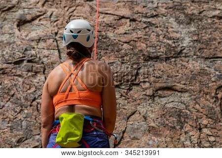A Close Up And Rear View Of A Healthy Caucasian Woman Wearing Orange Vest, Safety Hat, Harness And C