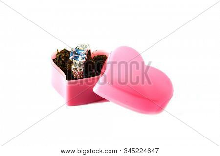 Wedding or Engagement Ring with Marijuana in a Heart Shaped Ring Box. Isolated on white. Room for text. Some people love Cannabis and Diamond Rings. Cannabis Weddings are a new trend in the USA. 