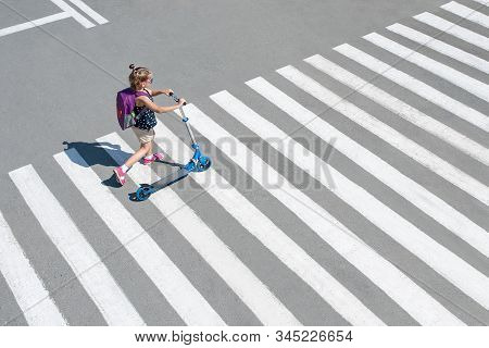 Girl Carrying Scooter And Crossing Road On Way To School. Zebra Traffic Walk Way In The City. Pedest