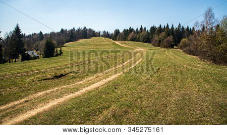 Springtime Mountain Meadow With Dirty Road, Trees Around, Isolated House And Clear Sky In Javorniky 