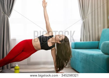 Fit Brunette Woman In Red Leggings And Black Top Standing In Side Plank After Doing Everyday Warm Up