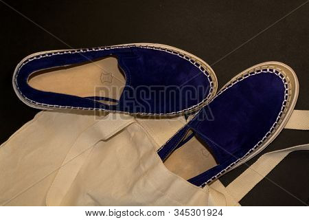 On Black Background Of The Shopping Bag, Shopper, Of Beige Cloth And Blue Slipons Of Suede. Street F
