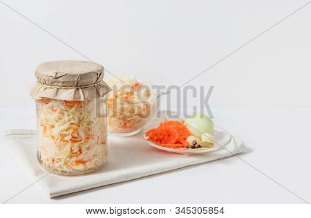 Homemade Sauerkraut With Carrots In A Glass Jar And Bowl On A White Wooden Background. Fermented Foo