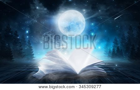 Open Book Magic. Dark Background Magic. An Open Book On A Wooden Table Under The Night Sky Against A