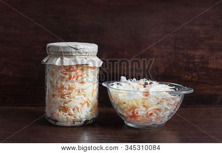 Homemade Sauerkraut With Carrots In A Glass Jar And Bowl On A Dark Wooden Background. Fermented Food