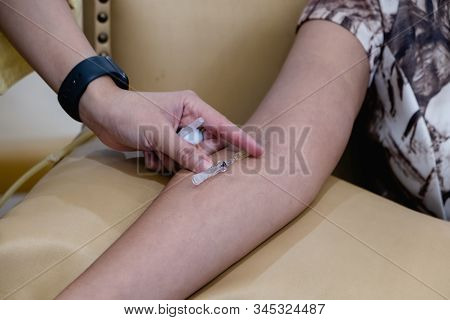 The Expert Is Piercing The Needle Into The Patient's Arm Sitting On A Yellow Leather Sofa Chair
