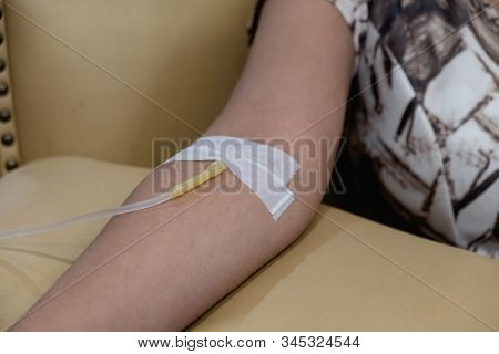 The Expert Is Piercing The Needle Into The Patient's Arm Sitting On A Yellow Leather Sofa Chair
