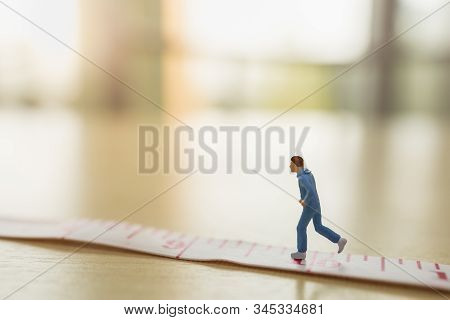 Sport And Fitness Concept. Close Up Of Man Runner Miniature Figure People Running On Measure Tape On