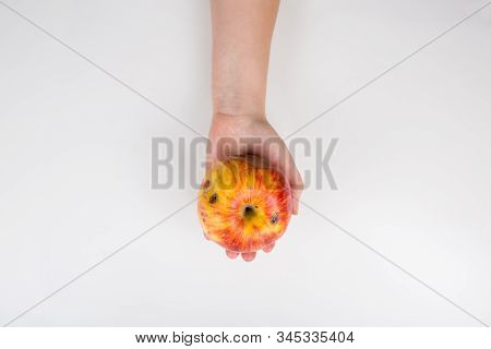 Close Up Of A Human Hand Holding A Slightly Degraded Apple Isolated On White Background With Copy Sp