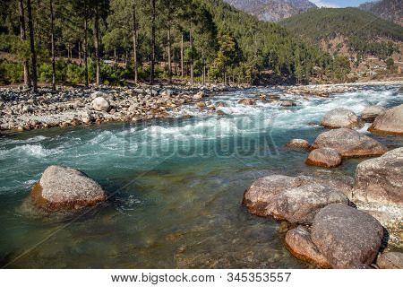 A Small Creek Flowing Through The Valleys Of The Himalayan Mountains With Big Rocks And Pebbles
