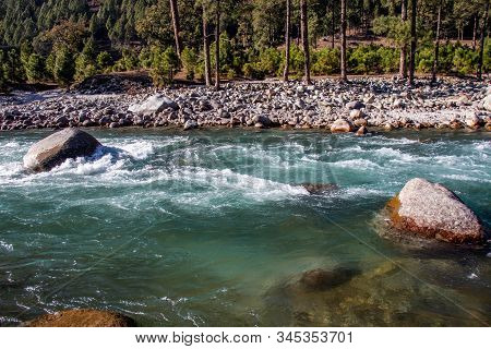A Small Creek Flowing Through The Valleys Of The Himalayan Mountains With Big Rocks And Pebbles