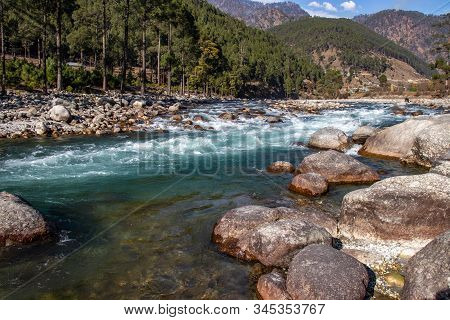 A Small Creek Flowing Through The Valleys Of The Himalayan Mountains With Big Rocks And Pebbles
