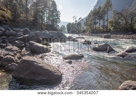 A Small Creek Flowing Through The Valleys Of The Himalayan Mountains With Big Rocks And Pebbles
