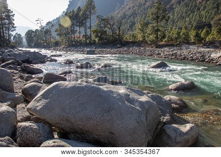 A Small Creek Flowing Through The Valleys Of The Himalayan Mountains With Big Rocks And Pebbles