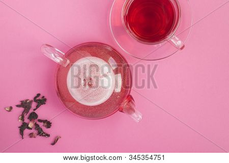 Hibiscus Or Karkade Tea In The Glass  Teapot And Glass Cup On The Pink Background. Top View. Copy Sp