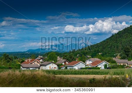 View Of A Mountain Town, Slopes Covered With Forest And Mountain Peaks In The Distance A Blue Sky Wi