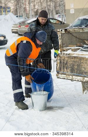 Worker Pours Water From A Barrel Into A Bucket