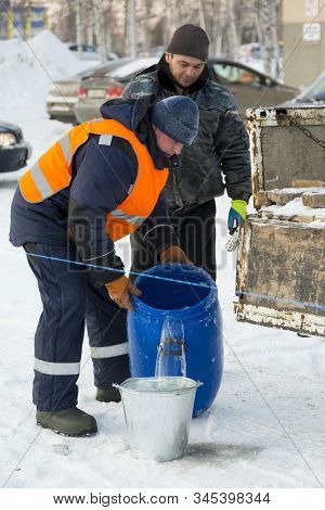 Worker Pours Water From A Barrel Into A Bucket