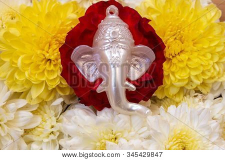 Face Of Lord Ganesha Placed Over Beautiful Rose And Chrysanthemum Flowers. Use For Religious Concept