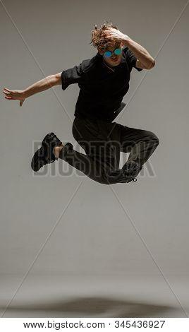 Guy Dancing Contemporary Dance In Studio. Neutral Grey Background. Acrobatic Bboy Dancer.