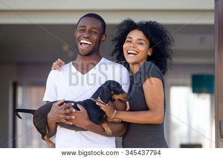 Portrait Of Excited Black Family Posing With Dog Near Home