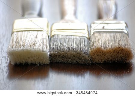 Three Wood Paint Brushes On A Wood Table