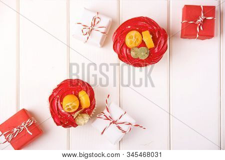 Tasty Festive Cupcakes And Small Christmas Gifts On Wooden Background, Top View. Christmas Holidays