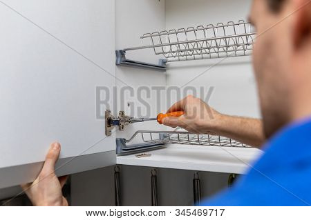 Handyman Doing Kitchen Cabinet Hinge Adjustment At Home