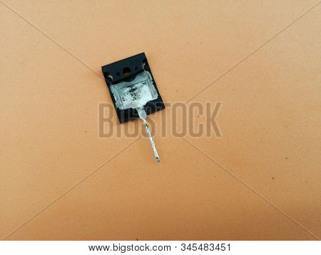 Part Of A Damaged Broken Bipolar Transistor With One Output On A Light Orange Background