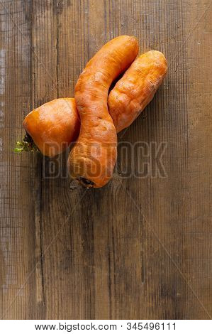 Two Curved Ugly Carrots On Brown Old Wooden Background With Copy Soace. Vegetables With Unusual Stra