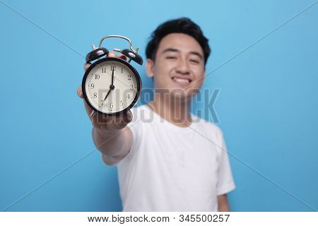 Young Asian Man Wearing Shite Shirt Shows Time On Clock With A Happy Expression, Time Management. Ha