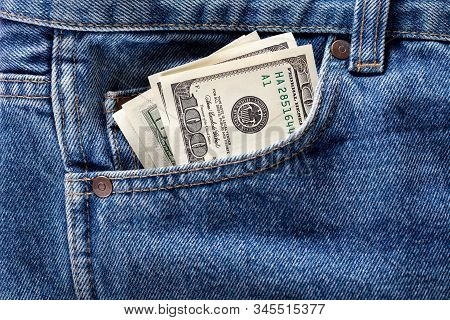 Us Dollar Banknotes In The Front Left Pocket Of Blue Jeans. Concept Of Saving Money Or Pocket Expens