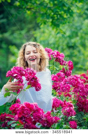 Young Smiling Woman Surrounded Rose Flowers. Tender Girl Enjoing Summer Time And Roseblush Blossom. 